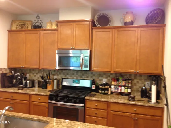 a kitchen with granite countertop a sink a stove and cabinets