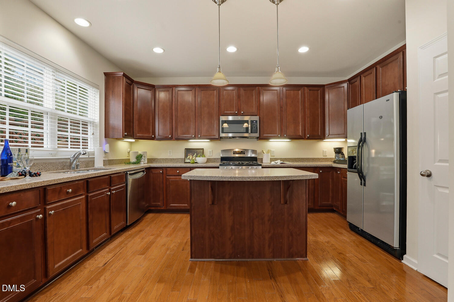 2510 Silverpalm Street Raleigh, NC 27612 - Photo 15 of 65 a kitchen with stainless steel appliances granite countertop wooden cabinets a refrigerator a sink a stove a microwave and wooden floors