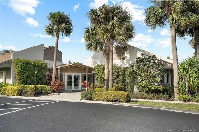 front view of a house with a yard and palm trees
