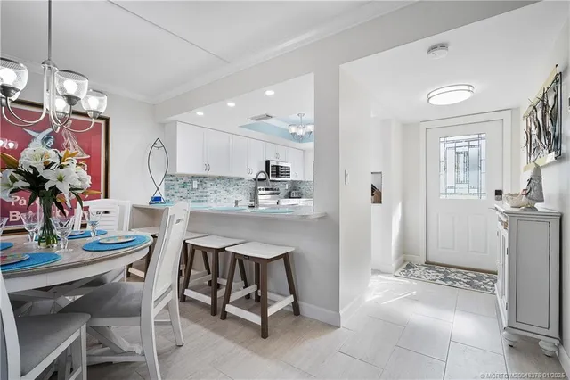 a kitchen with kitchen island a dining table chairs cabinets and stainless steel appliances