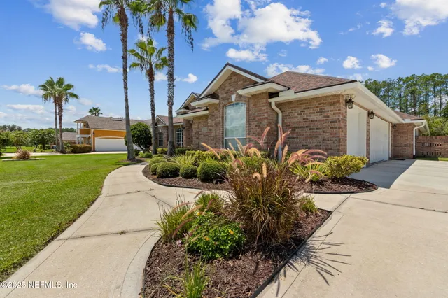 a view of a brick house with a large windows and flower plants