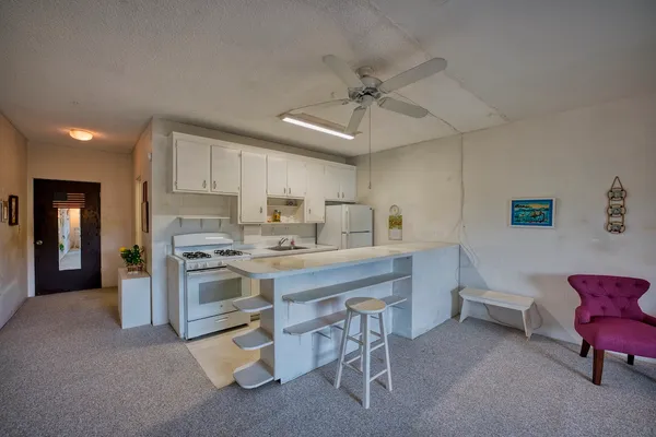 a kitchen with stainless steel appliances a sink a stove a refrigerator cabinets and chairs