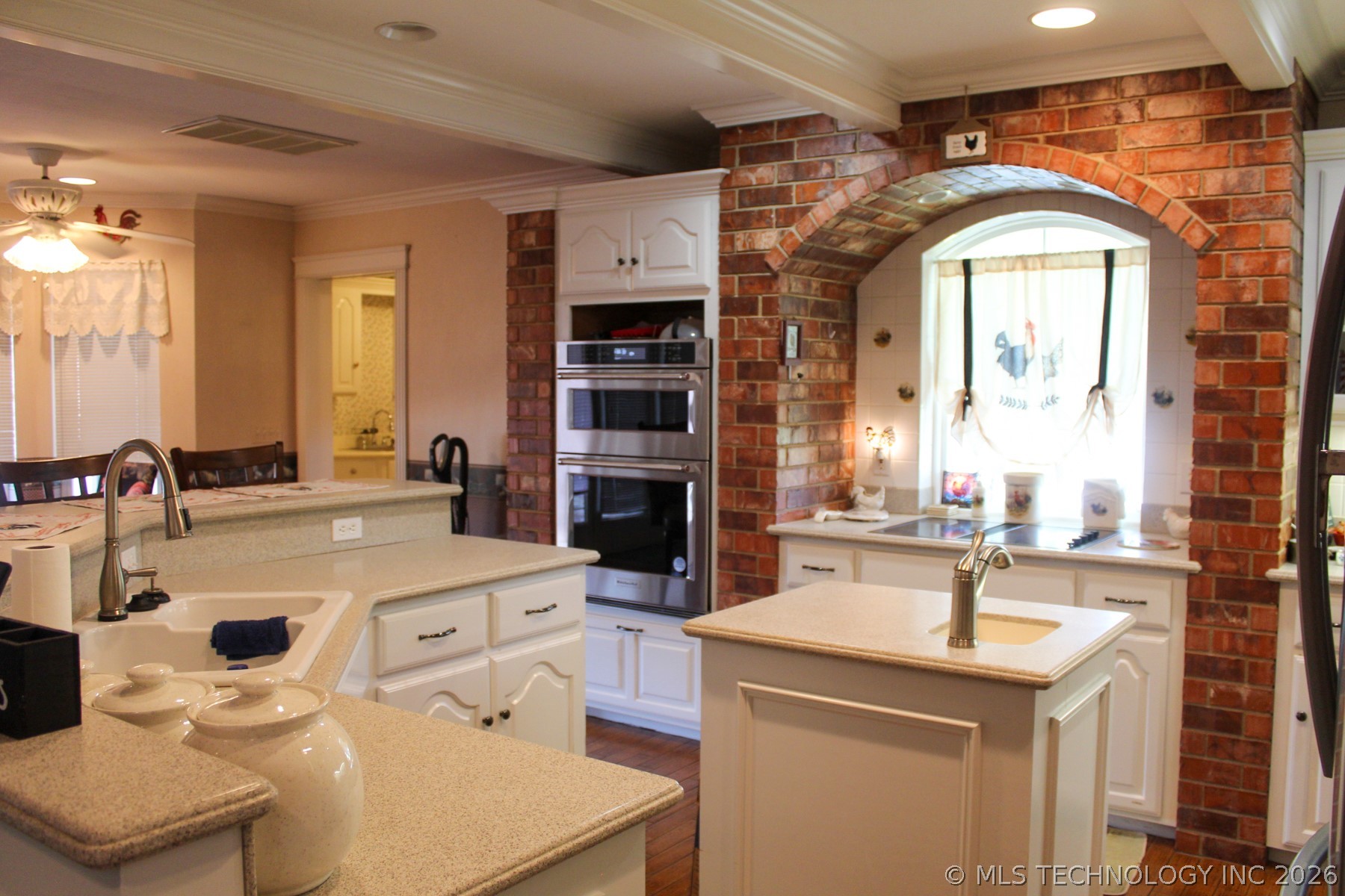 13248 North 3540th Road Maud, OK 74854 - Photo 49 of 98 Kitchen featuring a brick archway surrounding a window, built-in stainless steel double ovens, white cabinetry, and light-toned countertops