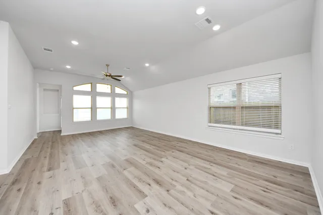 an empty room with wooden floor and windows