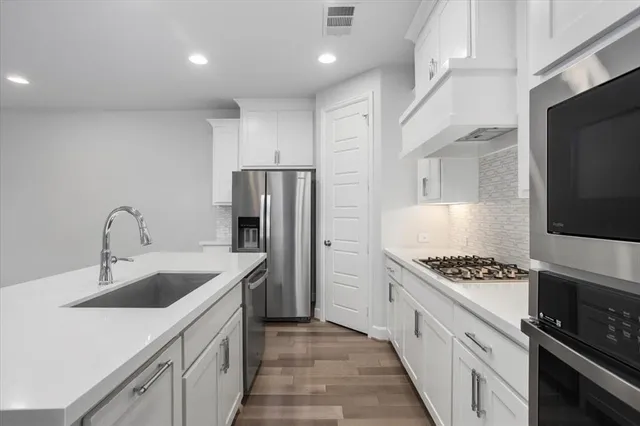 a kitchen with stainless steel appliances granite countertop a sink stove refrigerator and cabinets