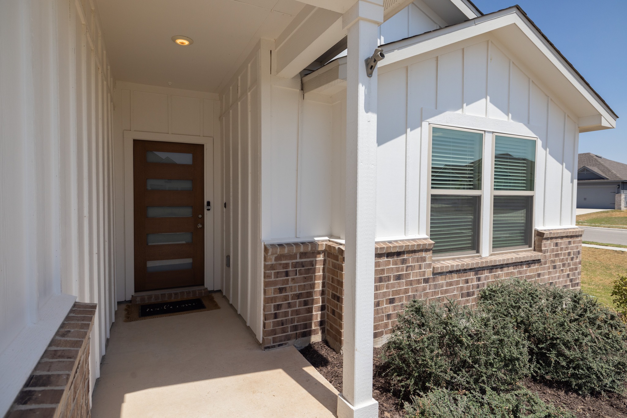 129 Maybelline Road Jarrell, TX 76537 - Photo 4 of 28 An inviting front porch with board and batten siding leads to a modern wood entryway.