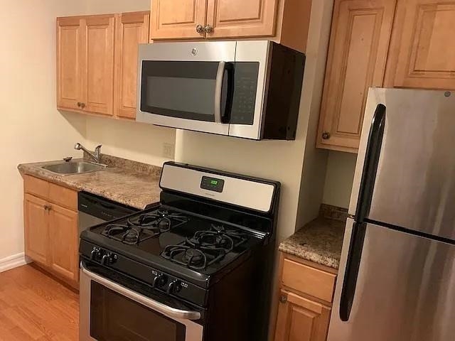 363 5th Street, Unit 2 Jersey City, NJ 07302 - Photo 5 of 7 a kitchen with stainless steel appliances granite countertop a stove microwave and refrigerator
