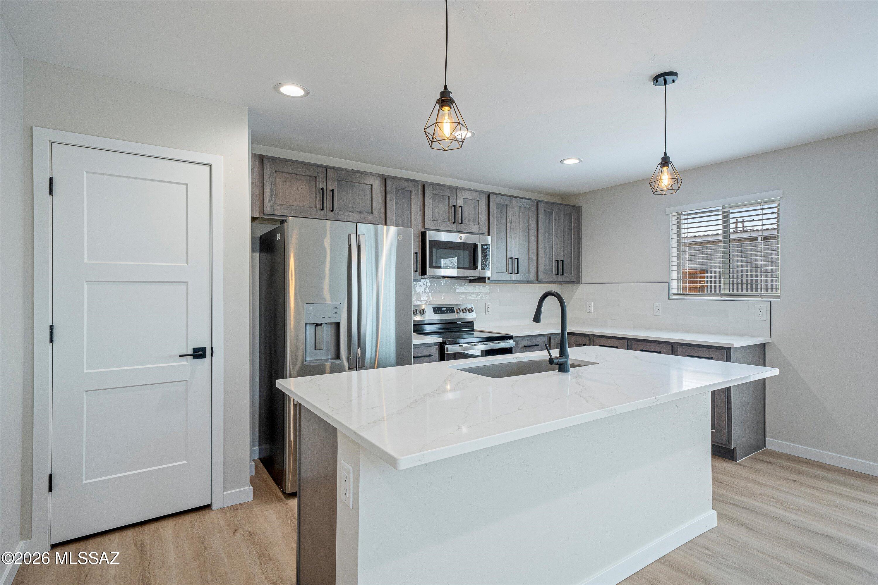 739 North Queen Avenue, Unit 2 Tucson, AZ 85705 - Photo 21 of 28 a kitchen with stainless steel appliances granite countertop a sink a stove a refrigerator and island with wooden floor