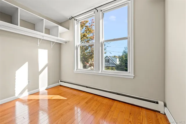 a view of an empty room with a window and wooden floor