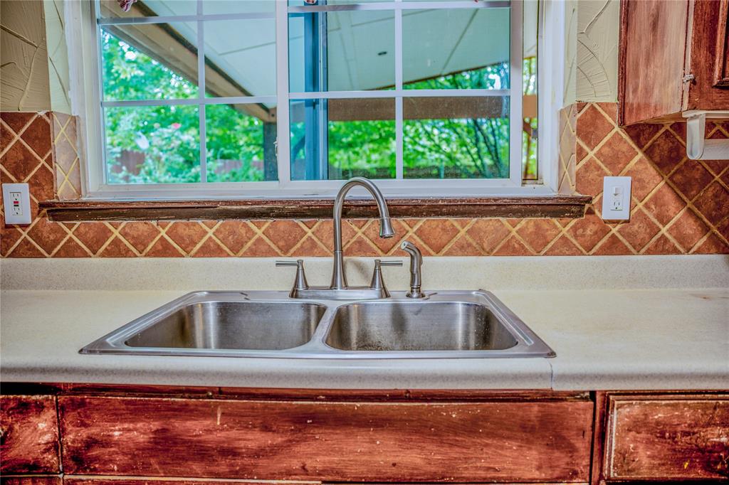 6317 Locust Street Rowlett, TX 75089 - Photo 13 of 34 Kitchen area featuring a double basin stainless steel sink with a gooseneck faucet, light-toned countertops, and a tiled backsplash
