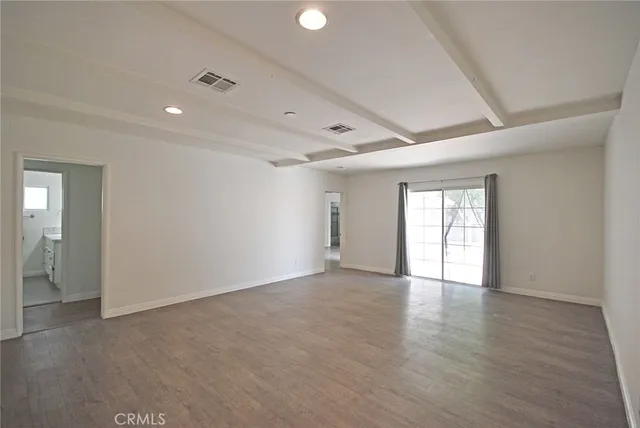 a view of empty room with wooden floor and kitchen