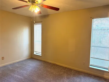 an empty room with a ceiling fan and a window