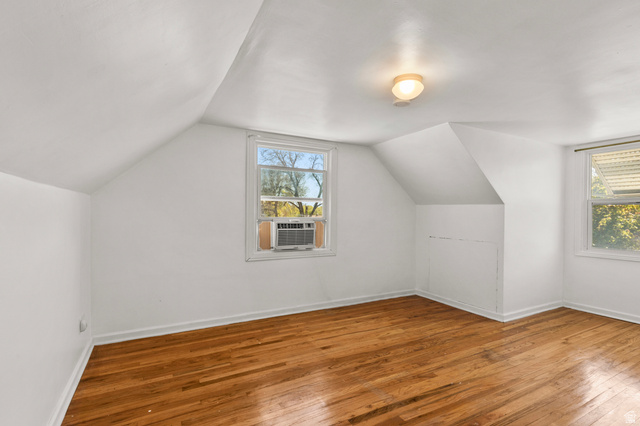658 North 100 East Logan, UT 84321 - Photo 16 of 26 Room featuring wood-finish flooring, two windows, sloped ceilings, a ceiling-mounted light fixture, and white painted walls