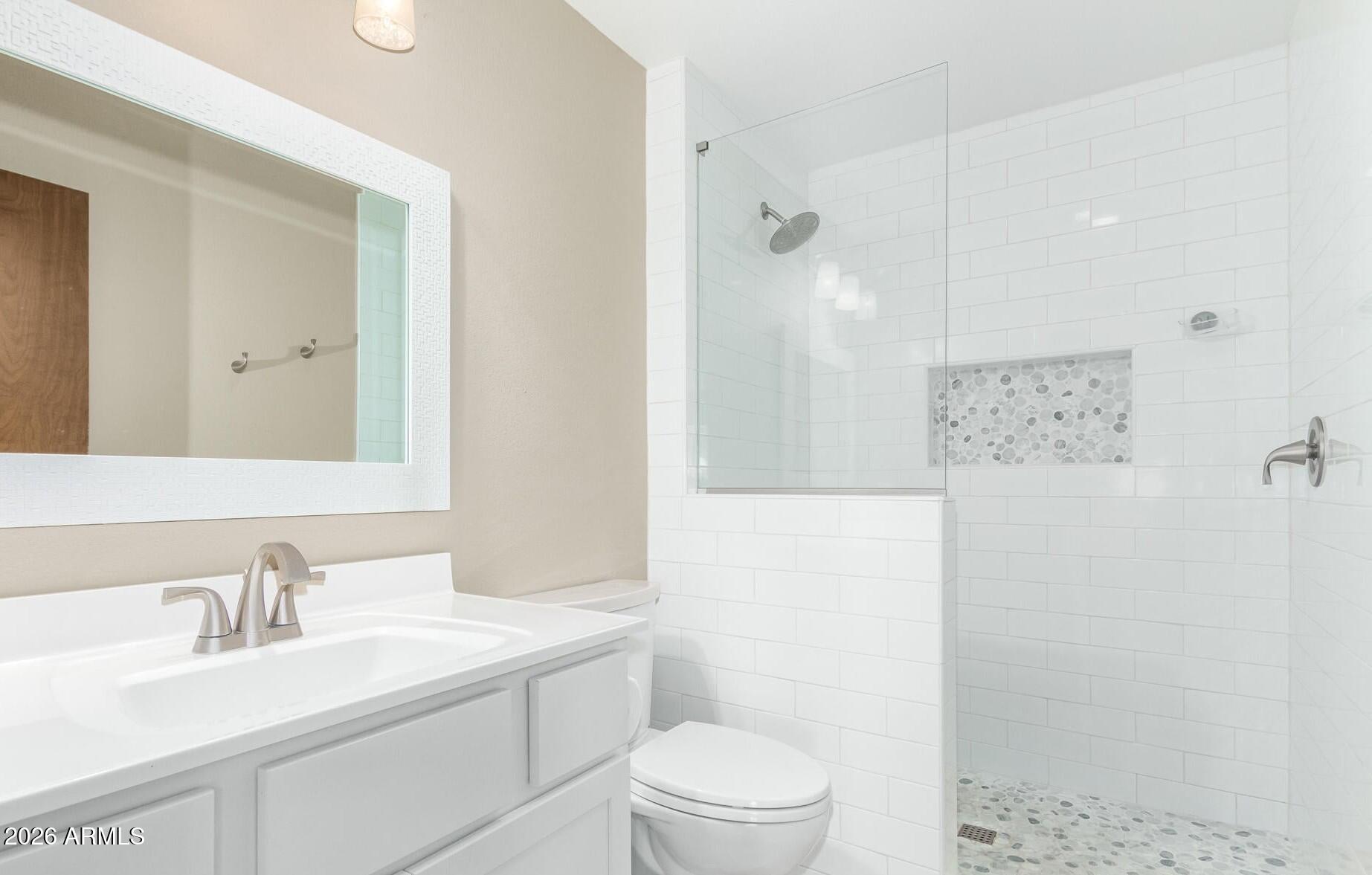 9845 West Royal Ridge Drive Sun City, AZ 85351 - Photo 3 of 28 a bathroom with a granite countertop sink a toilet a shower and a mirror