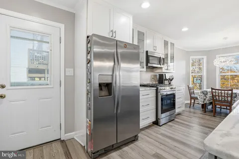 a kitchen with stainless steel appliances granite countertop a refrigerator a stove a sink a oven with a dining table and chairs