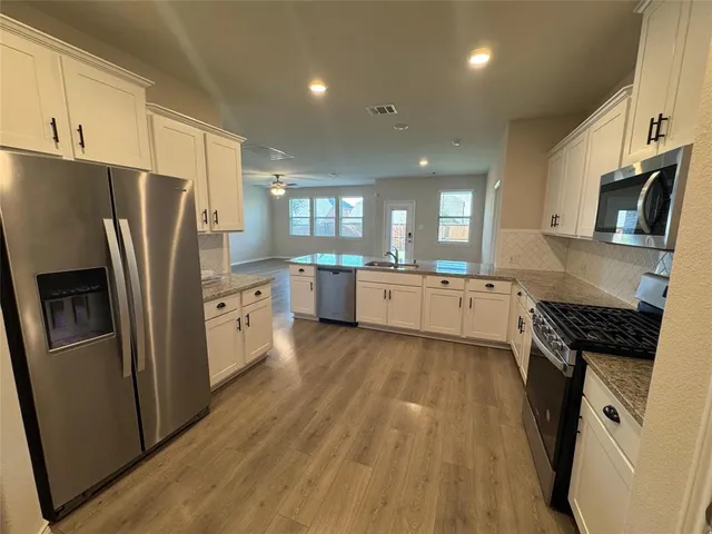 a large kitchen with stainless steel appliances granite countertop a stove a sink dishwasher and a refrigerator