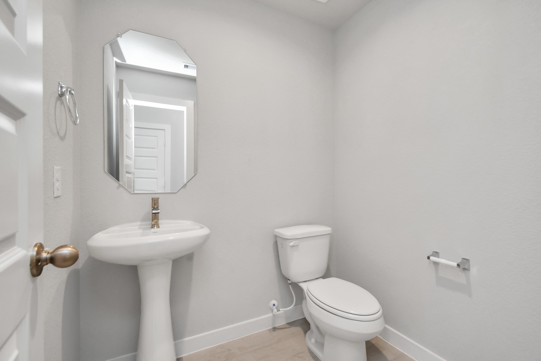 15111 Statice Trail Houston, TX 77044 - Photo 11 of 35 Experience modern elegance in this charming half bathroom, boasting a sophisticated 5-panel door, upgraded pedestal sink, contemporary hardware, and bright recessed lights. The warm paint palette bathes the area in a welcoming glow, creating a bright and inviting atmosphere. Sample photo of completed home with similar floor plan. Actual colors and selections may vary.