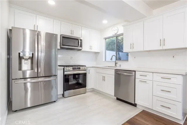 a kitchen with stainless steel appliances white cabinets and a refrigerator