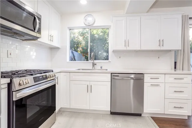 a kitchen with white cabinets appliances and sink