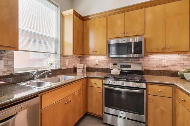 a kitchen with stainless steel appliances granite countertop a refrigerator a sink a stove and white cabinets