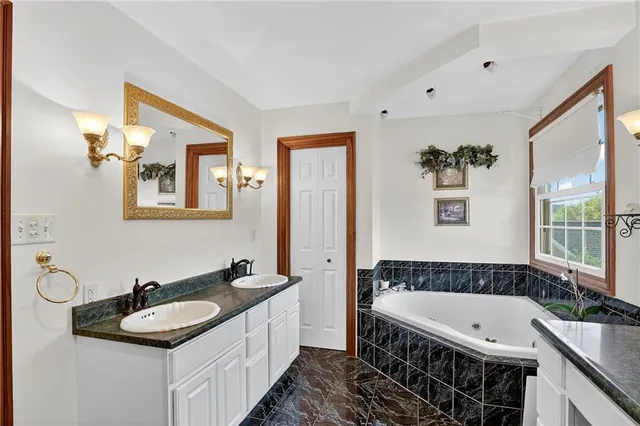 a bathroom with a granite countertop tub a sink and a large mirror