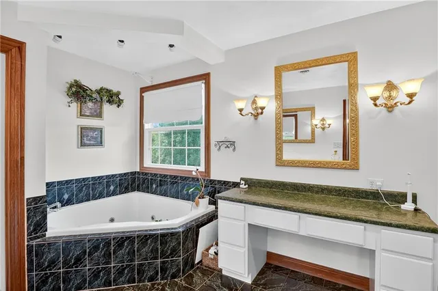 a bathroom with a granite countertop sink a mirror and a bathtub