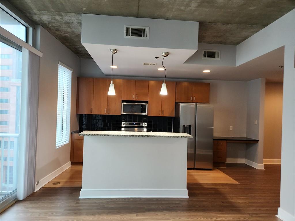 a view of a kitchen with stainless steel appliances wooden floor and living room view