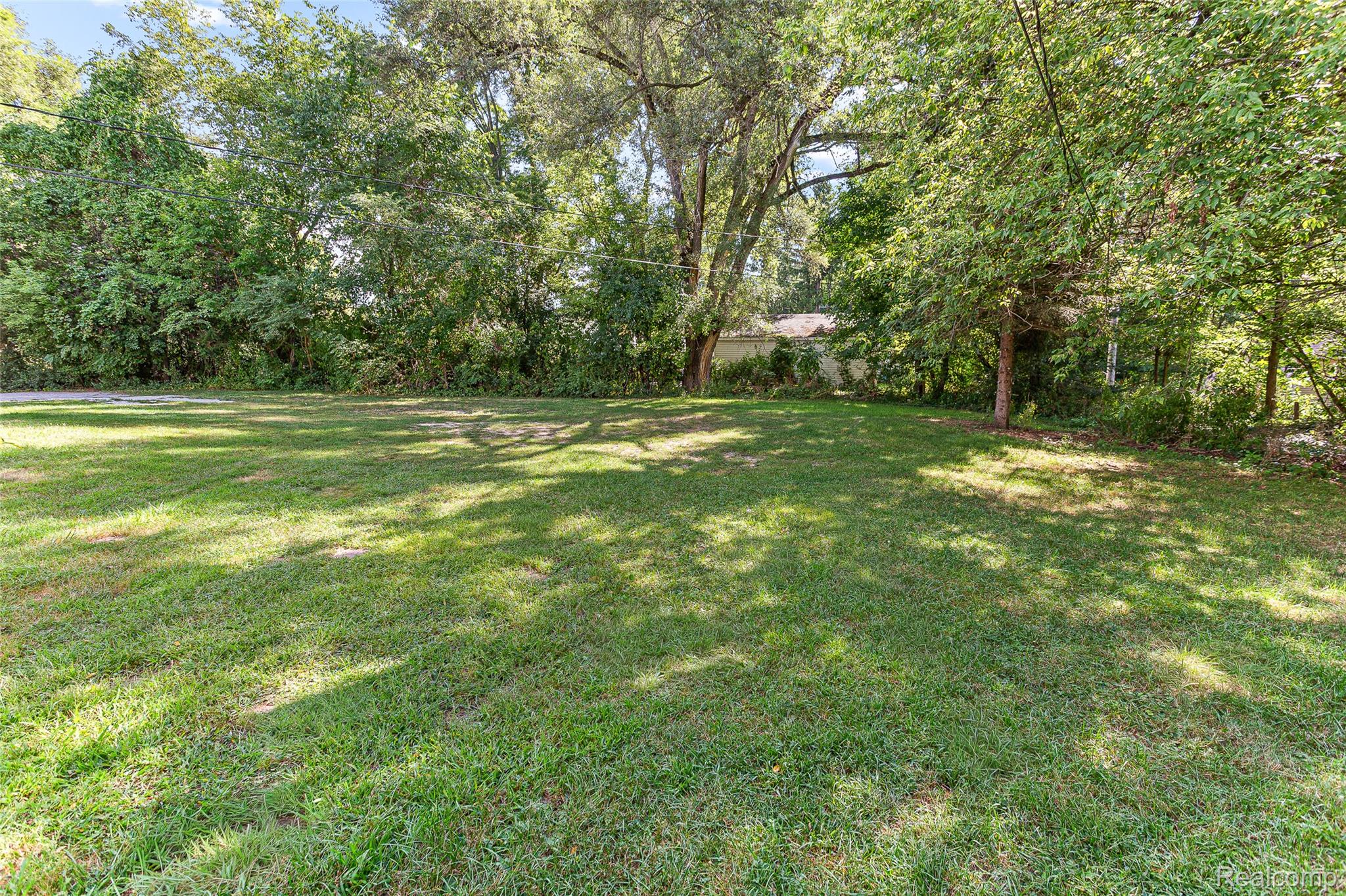 2550 Loon Lake Road Wixom, MI 48393 - Photo 34 of 36 Expansive grassy area surrounded by substantial mature trees