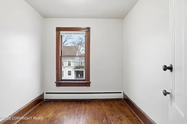 an empty room with wooden floor and windows