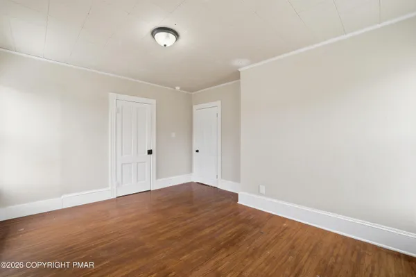 a view of empty room with wooden floor and fan