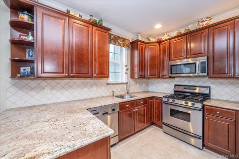 a kitchen with stainless steel appliances granite countertop wooden cabinets a sink and a stove