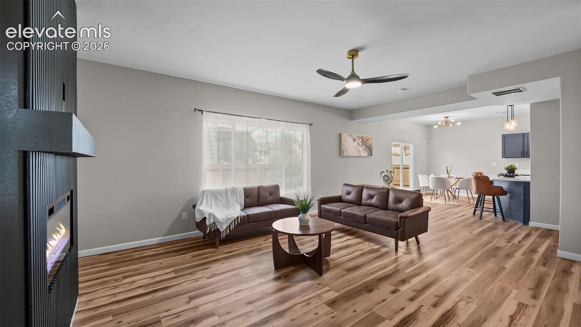 2044 Reed Grass Way Colorado Springs, CO 80915 - Photo 11 of 47 Open-concept living space featuring wood-finish flooring, a contemporary fireplace, and a ceiling fan