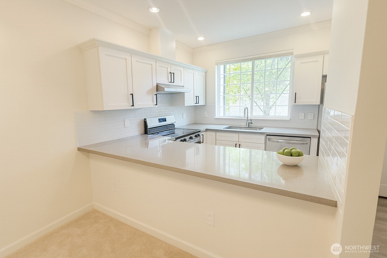 25025 Southeast Klahanie Boulevard, Unit D202 Issaquah, WA 98029 - Photo 2 of 23 a kitchen with stainless steel appliances a sink a stove a window and white cabinets