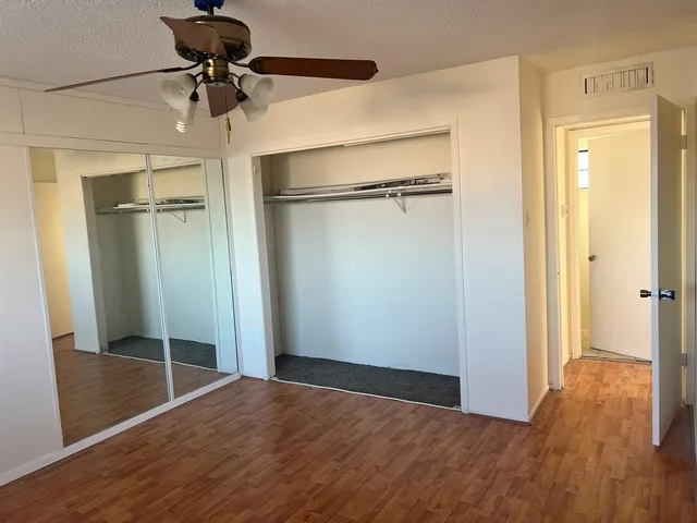 a view of empty room with wooden floor and fan