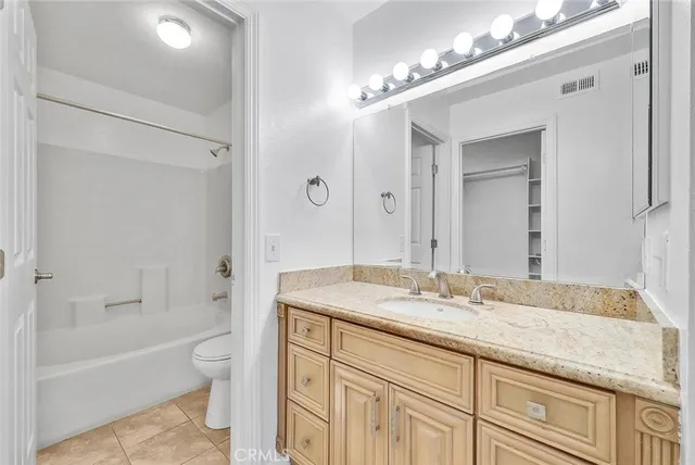 a bathroom with a granite countertop sink a toilet and bathtub