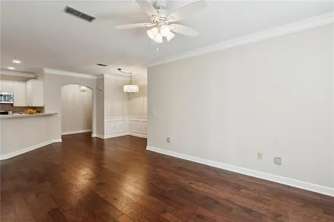 a view of an empty room with wooden floor and a kitchen