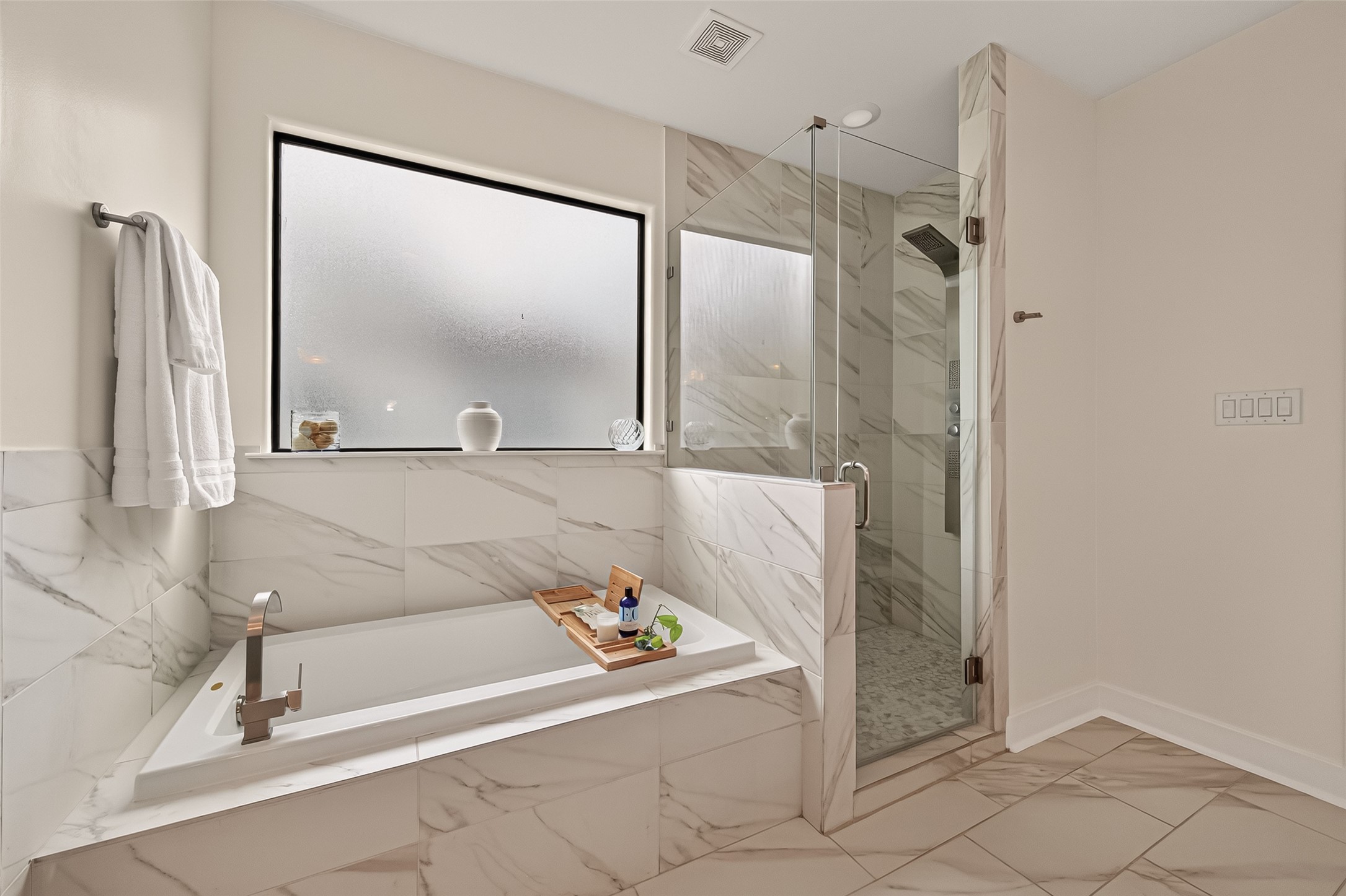 1767 Michigan Street Houston, TX 77006 - Photo 24 of 33 The primary bathroom features a large soaking tub with elegant marble tile, a sleek glass-enclosed shower, and a frosted window for privacy.