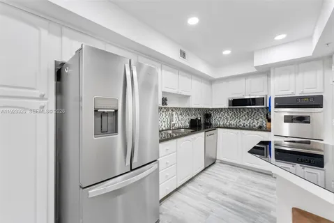 a kitchen with granite countertop a refrigerator and a stove top oven