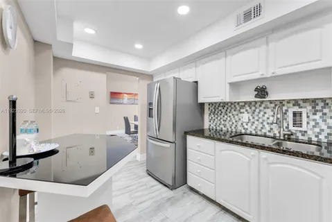 a kitchen with granite countertop a refrigerator and a sink