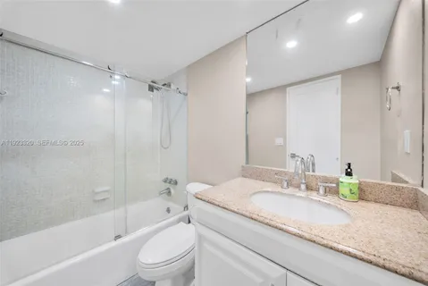 a bathroom with a granite countertop sink a toilet and shower