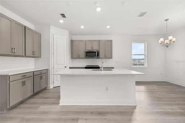 a kitchen with stainless steel appliances granite countertop a sink a stove a microwave a center island and cabinets