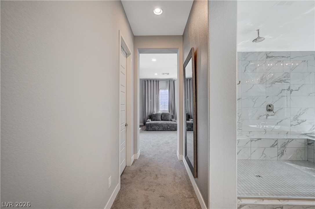 3943 Reyes Avenue Las Vegas, NV 89141 - Photo 43 of 95 A well-lit corridor provides a seamless transition to a bedroom, complemented by a spacious shower with sleek tile work.