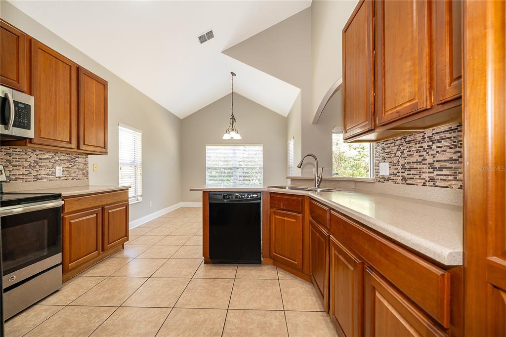 6825 Dolce Way Orlando, FL 32819 - Photo 17 of 40 a kitchen with stainless steel appliances granite countertop a stove a sink and a microwave