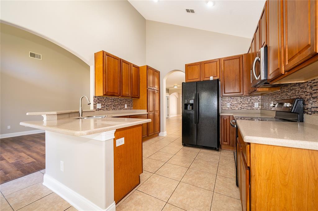 6825 Dolce Way Orlando, FL 32819 - Photo 19 of 40 a kitchen with stainless steel appliances granite countertop a refrigerator a stove and a sink with wooden cabinets