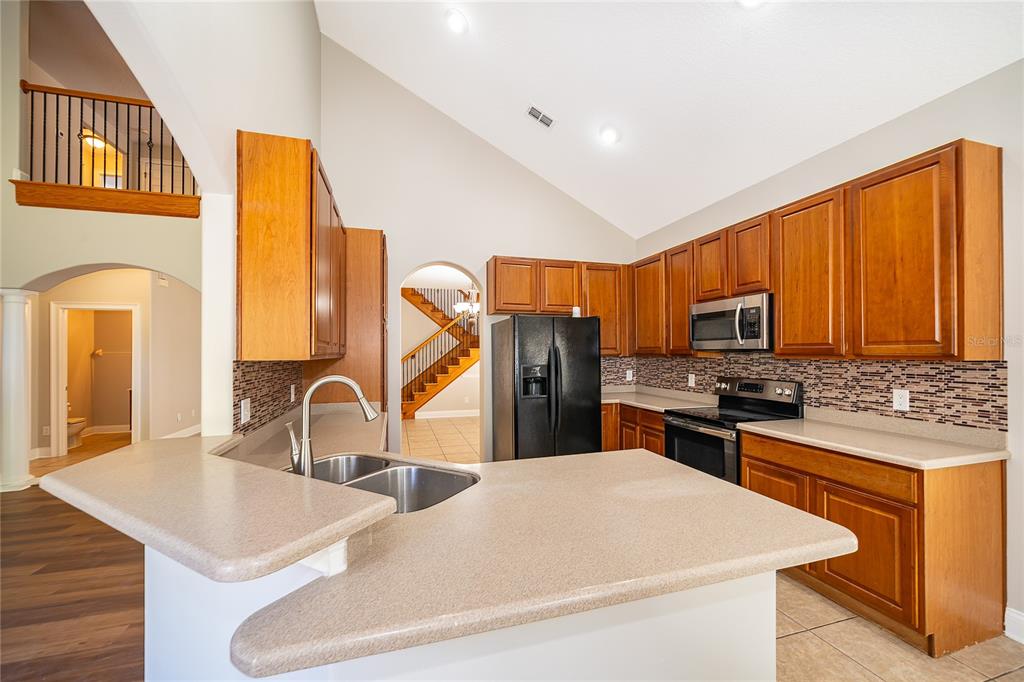 6825 Dolce Way Orlando, FL 32819 - Photo 20 of 40 a kitchen with stainless steel appliances granite countertop a sink a stove and refrigerator
