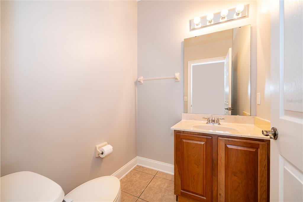 6825 Dolce Way Orlando, FL 32819 - Photo 27 of 40 a bathroom with a granite countertop sink a toilet and a mirror