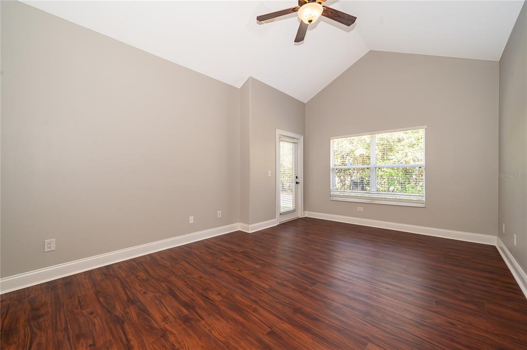 6825 Dolce Way Orlando, FL 32819 - Photo 28 of 40 an empty room with wooden floor chandelier fan and windows