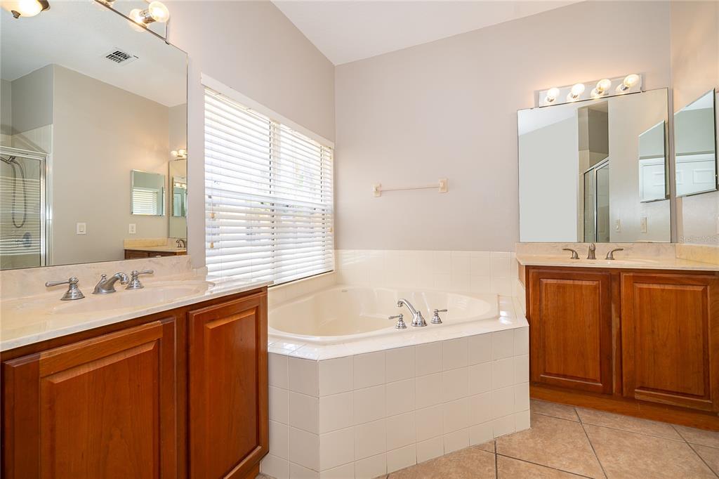 6825 Dolce Way Orlando, FL 32819 - Photo 31 of 40 a bathroom with a tub sink and mirror
