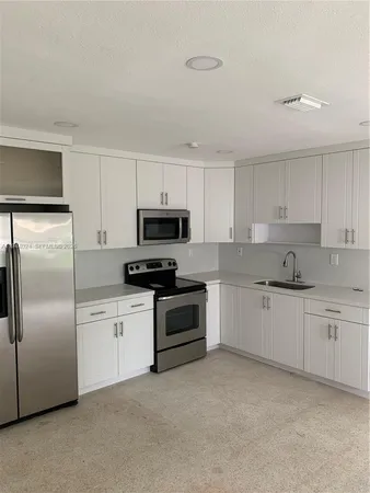 a kitchen with granite countertop white cabinets and stainless steel appliances