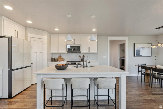 882 Spring Dew Lane Lehi, UT 84048 - Photo 11 of 46 Kitchen featuring white cabinets, freestanding refrigerator, dark wood-style floors, and a center island with sink